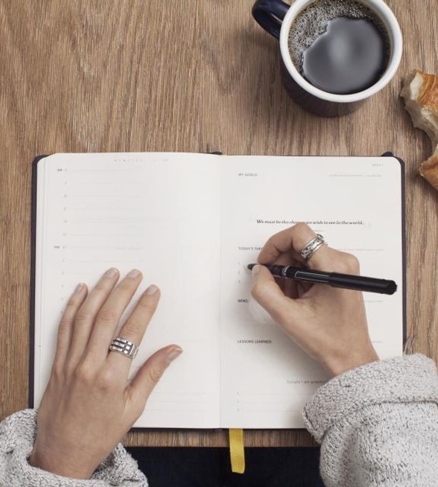 A local business owner writing out a growth plan next to a cup of coffee